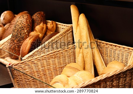 Baskets with various kinds of fresh baked bread on the shelf in the store.