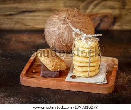 Homemade organic coconut cookies, diet candy bars and whole coconut on a wooden background. Gluten-free, low in carb sweets with coconut and coconut flour. Keto diet snack. Healthy diabetic dessert