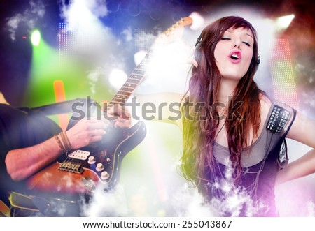 Beautiful woman listening to music with headphones. Live music background with guitar and bright lights on stage. Live music and party concept.