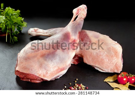 Fresh and raw meat. Leg of lamb uncooked tomato and pepper on black background