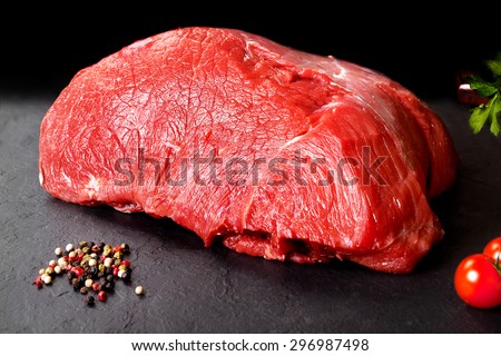 Fresh and raw meat. Whole piece of red meat ready to cook on the grill or BBQ . Background black blackboard