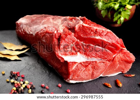 Fresh and raw meat. Whole piece of red meat ready to cook on the grill or BBQ . Background black blackboard