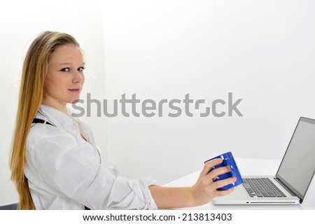 beautiful young woman working with computer and cup of tea in the hand