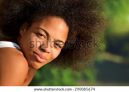 young happy and  pretty curly afro woman closeup portrait on natural background