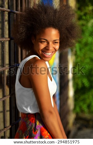 young happy and  pretty afro woman standing and laughing  near old building
