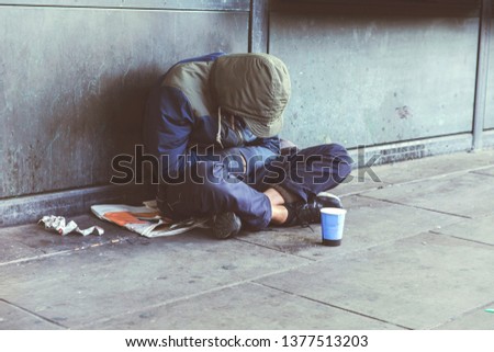 Homeless adult man sitting on the street in the shadow of the building and begging for help and money. Problems of big modern cities. Indifference of people. Social issues. ストックフォト © 