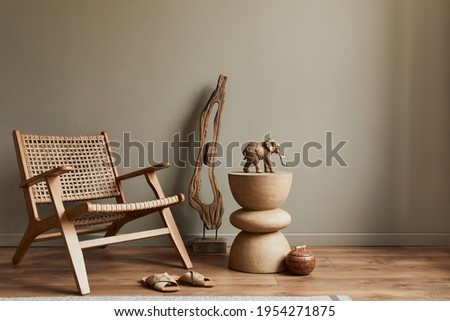 Stlish interior of living room with rattan armchair, wooden stool, elephant figure and decoration in modern home decor. Copy space. Template.