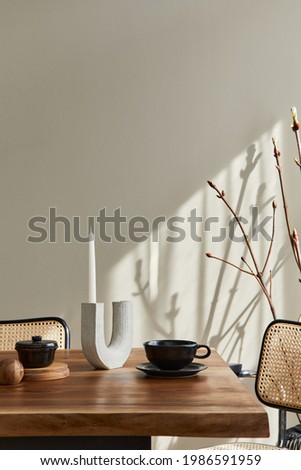 Minimalist concept of dining room interior with wooden family table, design chairs, candle stick, cup of coffee, tableware, beige wall and personal accessories. Copy space. template.