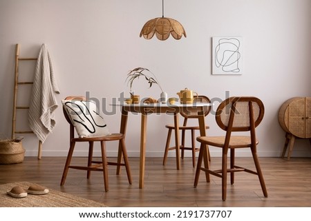 Boho and cozy space of dinning room with round family table, rattan chairs, design pedant lamp, commode, carpet, decoration and personal accessories. Minimalist home decor. Template.	
 Imagine de stoc © 
