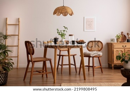 Boho and cozy space of dinning room with round family table, rattan chairs, design pedant lamp, commode, plants, decoration and personal accessories. Minimalist home decor. Template.	
 Imagine de stoc © 