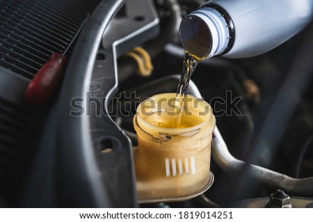 Auto mechanic filling DOT 4 brake fluid in brake fluid reservoir. Foto stock © 