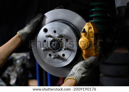 Auto mechanic installing two piston brake calipers and disc brake rotor. Foto d'archivio © 