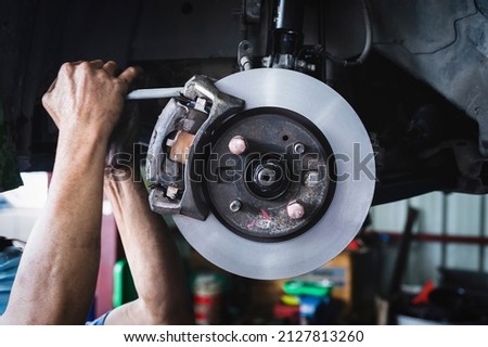Car mechanic installing New Front Brake Pads and Brake Rotors. 商業照片 © 