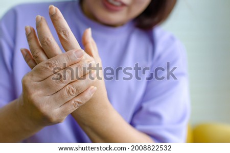 Woman using hand to hold other her palm with feeling pain, hurt and tingling. Concept of Guillain barre syndrome and numb hands disease. 商業照片 © 