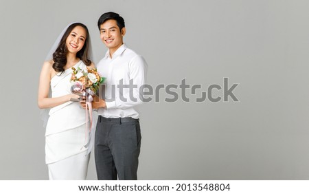 Young attractive Asian couple, man wearing white shirt, woman wearing white dress with wedding veil holding bouquet of flowers together. Concept for pre wedding photography. Сток-фото © 