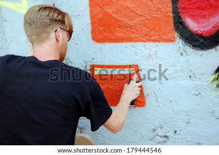 SAINT-PETERSBURG, RUSSIA, JULY 9,  2013: Graffiti artist draws a picture on the wall; artist paints background, St-Petersburg