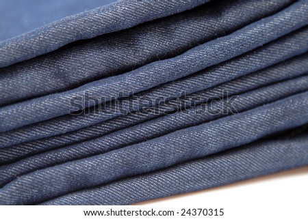 folded pile of blue denim jeans on white background