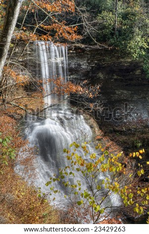Beautiful tall waterfall viewed through colorful autumn leaves.