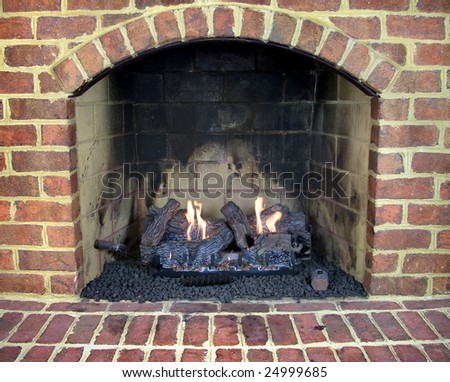 Close up of brick gas fireplace with a lit fire.