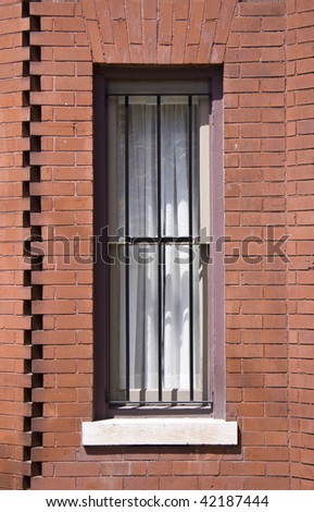 Close up detail of a brick home\'s window with security bars.