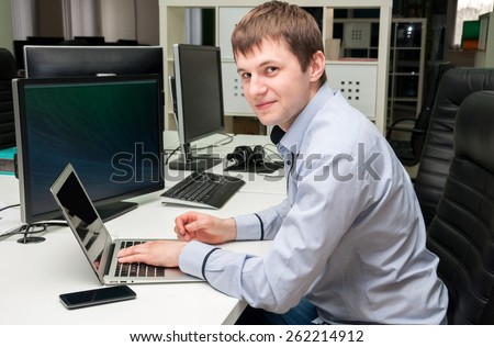 Young handsome happy man with computer in the office. Programming