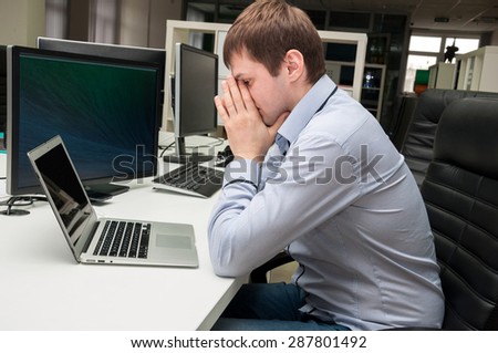 Young handsome man with computer in the office. Thinking over task in programming