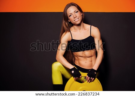 beautiful girl in a gym near gray orange wall