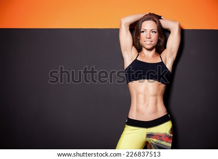 beautiful girl in a gym near gray orange wall