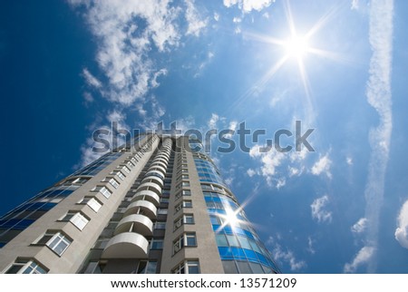 Catch the sun. Tall office or residential building on blue sky with clouds. Wide-angle lens used.