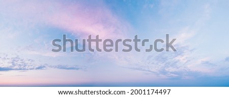 Calm, quiet, gentle clouds - a wide panoramic view of the sky before sunset. Pink clouds in blue clear skies on a summer evening. Panorama of the blue-pink sunset sky - the gentle sky on the horizon 商業照片 © 