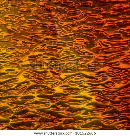 Image of an amber colored stained glass window with a wave texture, square format