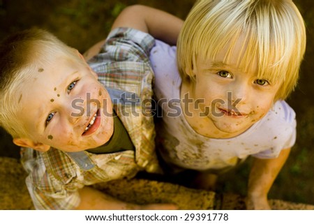 Toddler Boy and girl - dirty from playing in the mud, hugging each other