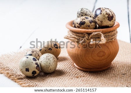 raw quail eggs in a wooden bowl on a burlap background.