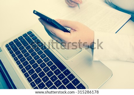 Business person working on computer and phone.