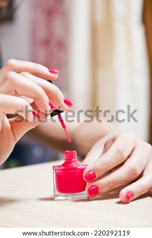 Female carefully painting her fingernails.