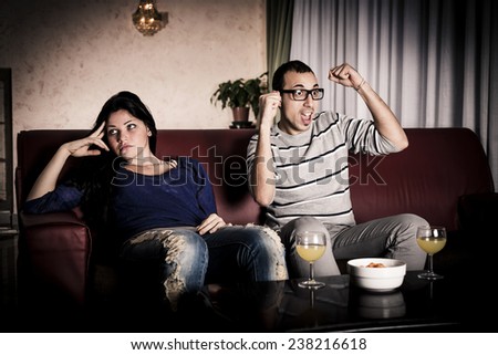Man watching sports and woman bored. Conflict about the tv program.