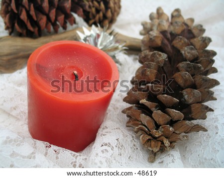 Christmas indoor scene .. red candle, pinecones, driftwood log and white lace.