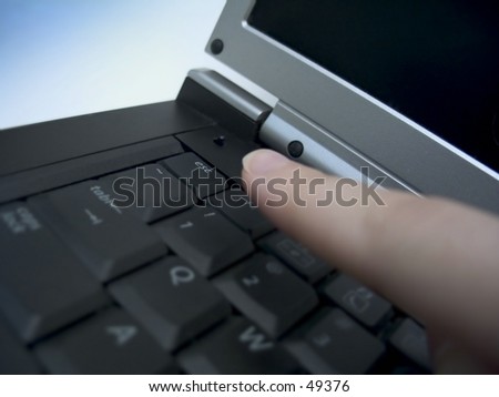 Finger about to press the escape key on a laptop. Focus on the esc. key.