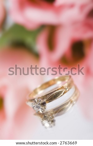 A gold engagement ring with some pink flowers