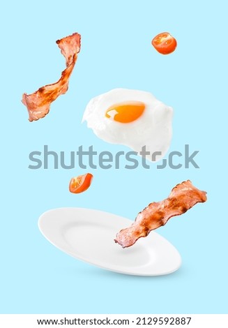 Bacon, tomatos and egg as English breakfast levitate over a plate on a blue background 商業照片 © 
