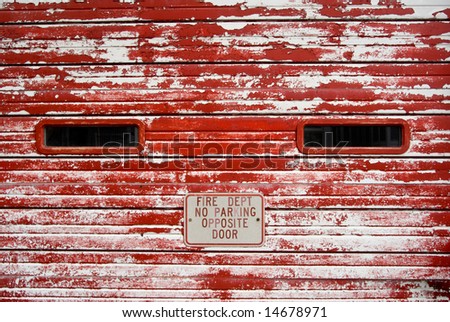 Vintage fire department wooden garage door with peeling, faded red paint