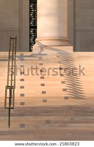 Shadows cast by setting sun on marble stairs, handrail and column
