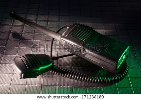 Two way radio and microphone with a green gel to the right