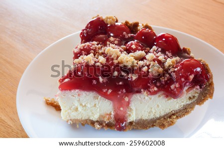 Cheesecake slice with cherries atop and a graham cracker crust