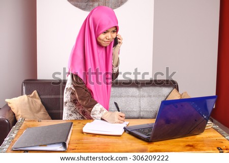 young muslim women office worker using laptop and talking on the phone at her office