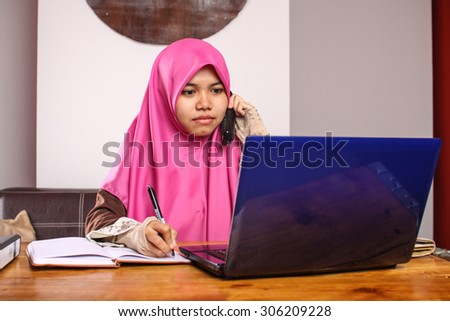 young muslim women office worker using laptop and talking on the phone at her office