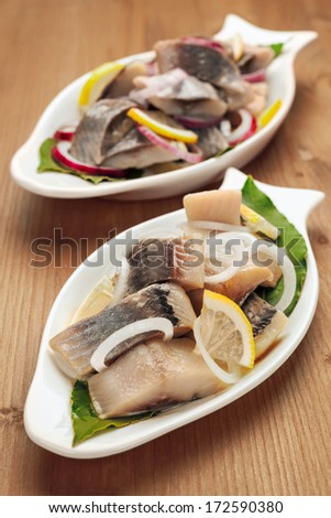 Seafood appetizer herring fish fillet with vegetables, white plates in the form of fish
