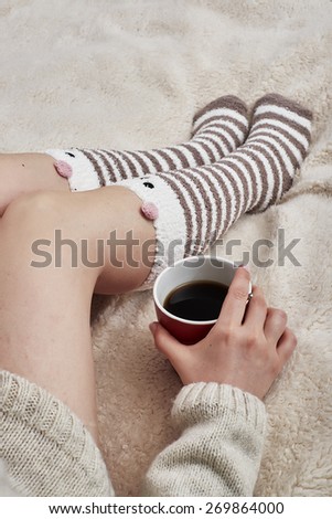 Woman on bed with bear socks and cup of coffee