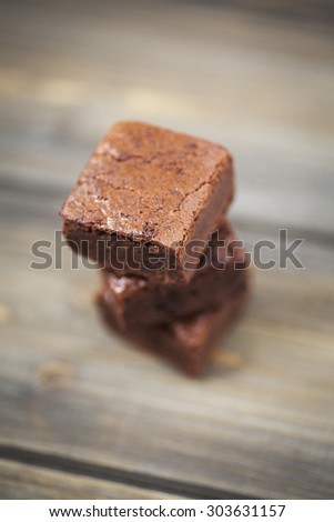 Stack of three pieces of chocolate brownie cake on a wooden background.