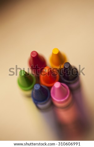 Six colourful wax crayons on a wooden background. Shot from above. Copy space above